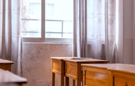 A peaceful, empty classroom with sunlight streaming through the window onto wooden desks.