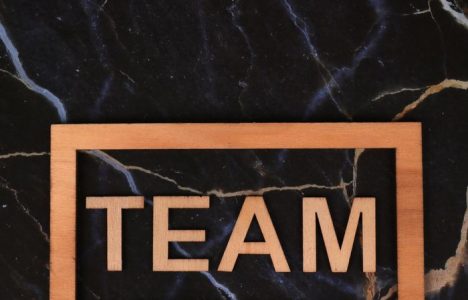 Wooden frame spelling 'TEAM' on a black marble surface, symbolizing collaboration.